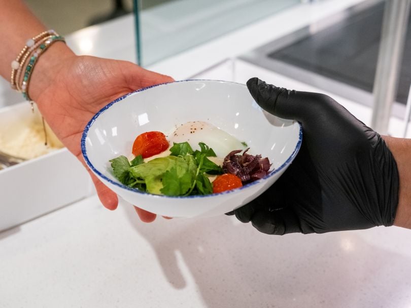 A Sifted worker hands a bowl of food to an employee during a Sifted-catered meal
